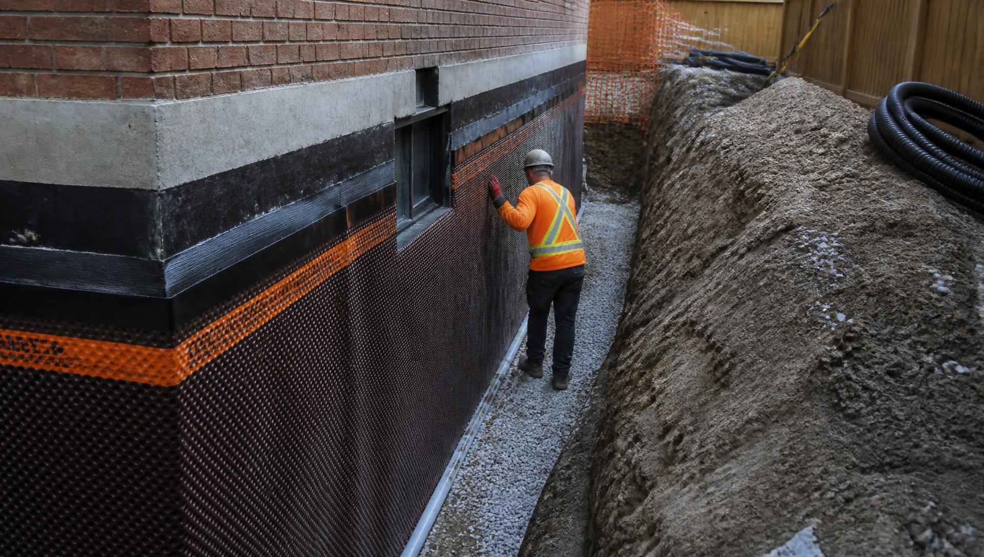 Waterproofing crew applying membrane to a residential foundation wall in Toronto